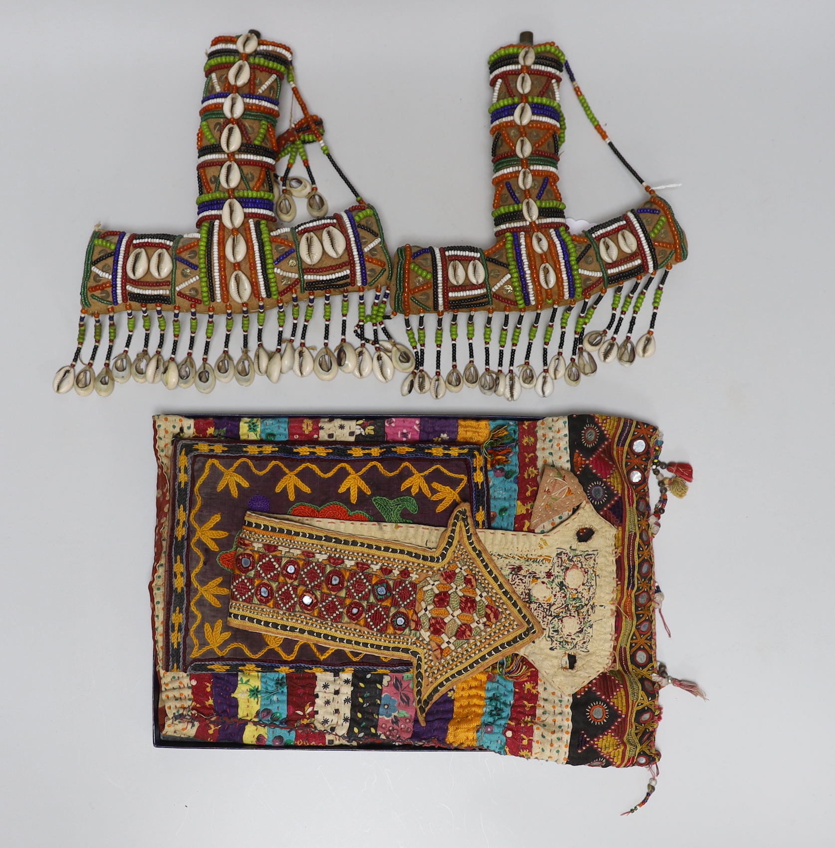 19th and 20th century textiles: An Indian mirrored and patchwork bag, a smaller embroidered bag, an ‘arrow’ shaped mirrored panel and two Omani shell and beaded ‘anchor’ shaped hangings, ‘arrow’ hanging 45cm long (5)